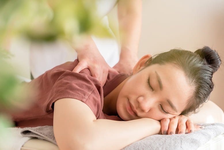 女性が横になって施術してもらっている様子