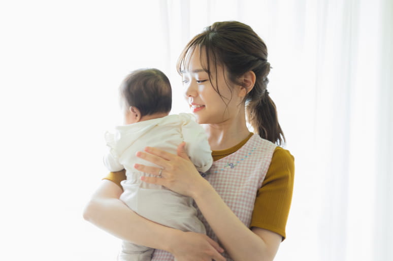 赤ちゃんを見つめながら両手で抱っこしている女性の姿