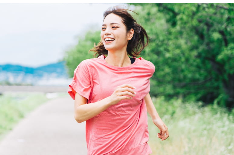 女性が緑が見える場所で走っている様子