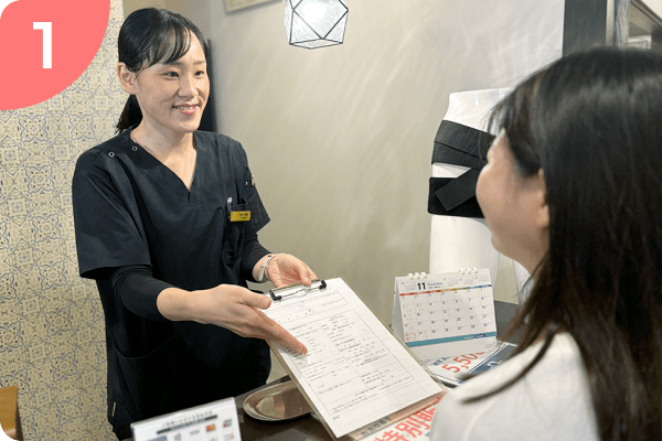 受付で問診票を差し出す女性スタッフの画像